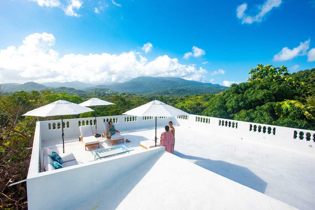Guests relax on the white rooftop of Casa Alternavida, surrounded by a lush tropical forest in Puerto Rico.