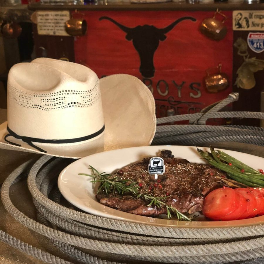 A white cowboy hat beside a steak dinner. 