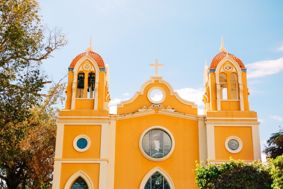 La iglesia de estilo misión española de color amarillo brillante con vista a la plaza del pueblo en Añasco