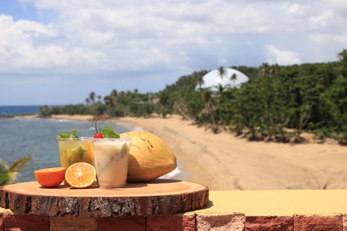 Cocktails and fruit rest on a tray in front of Domes Beach in Rincon, Puerto Rico.