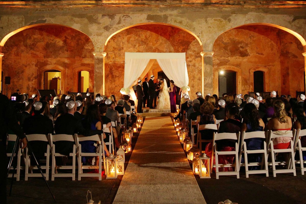 A bride and groom are married during a traditional Jewish wedding at a historic site in Puerto Rico.