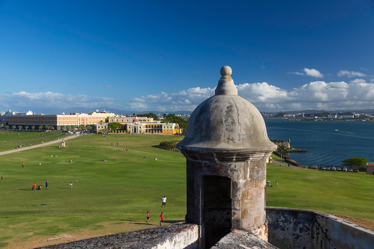Personas acercándose al Castillo San Felipe del Morro en el histórico San Juan en un día soleado.