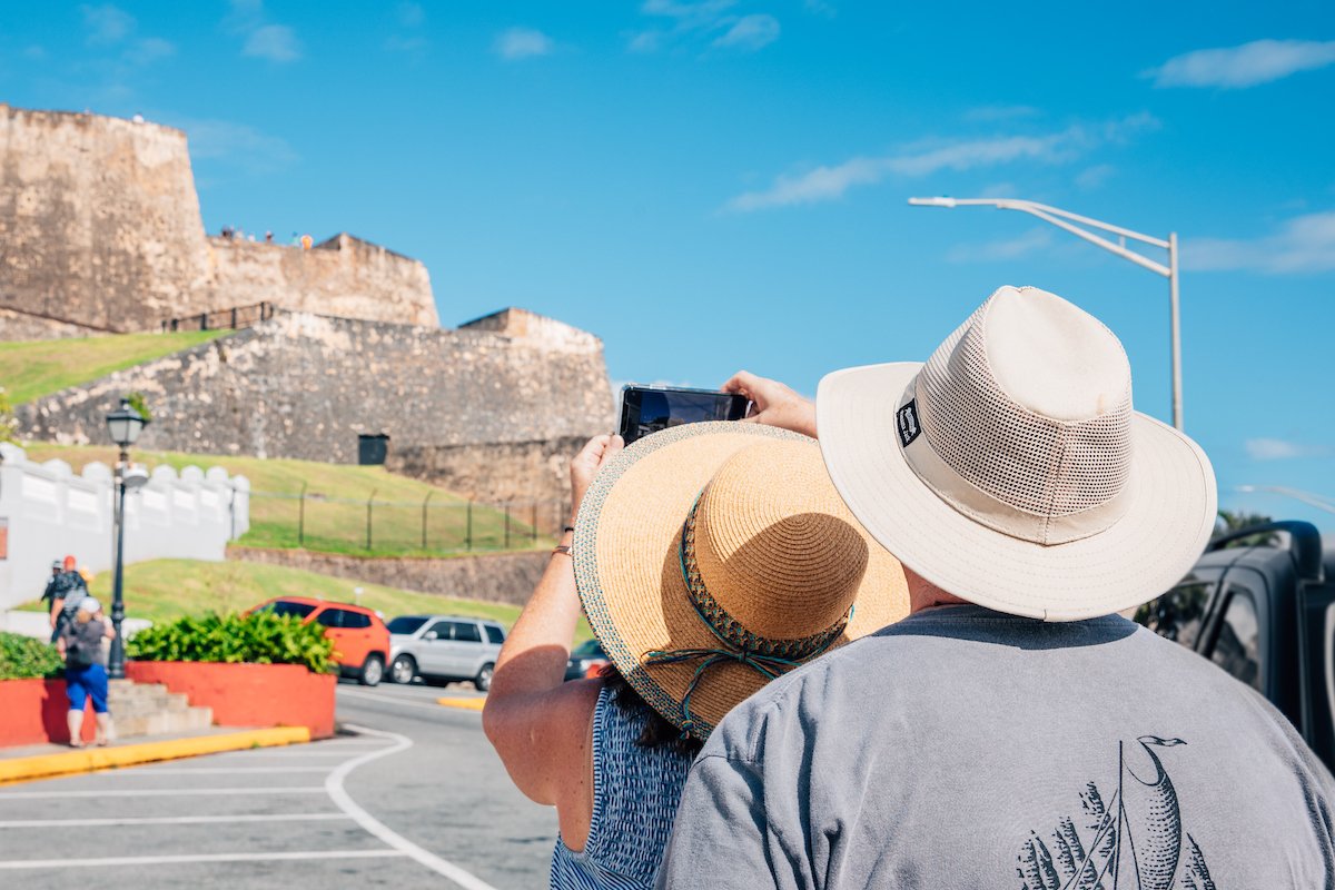 Una pareja, una mujer y un hombre, tomando fotos de monumentos históricos en el Viejo San Juan.