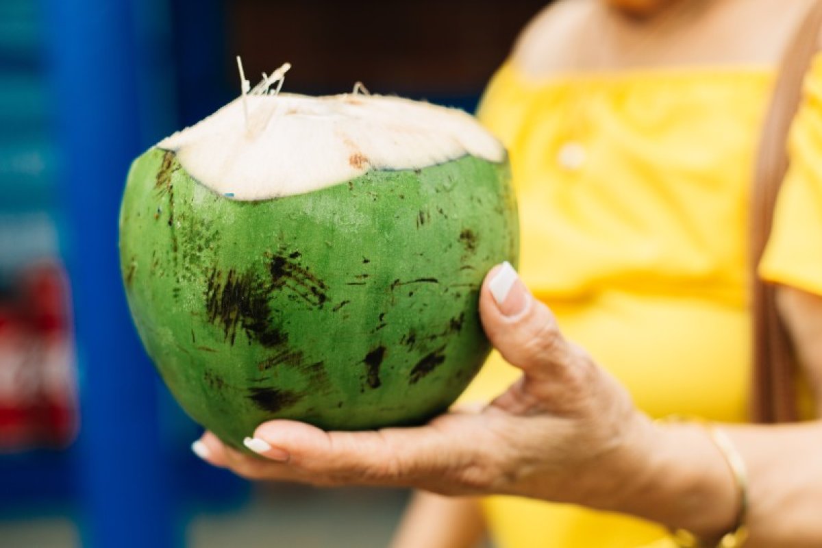 A woman holds a fresh coconut at the Kioskos de Luquillo