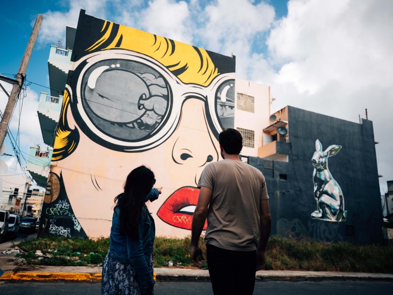 Dos personas admiran los murales en Santurce.