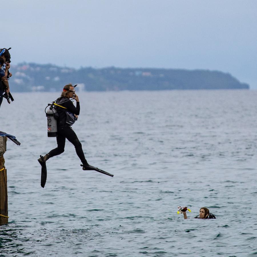 Dive instructor jumps into ocean at Crash Boat Beach.