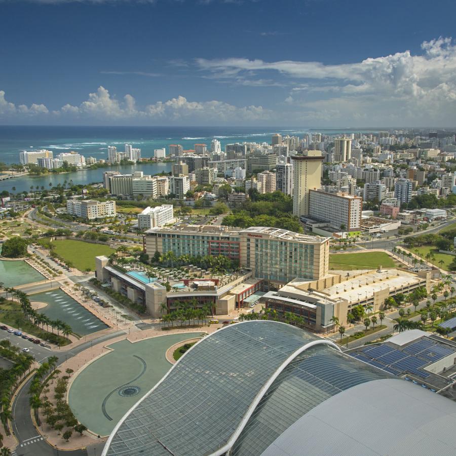 An aerial view of the Puerto Rico convention center in the foreground with the city rising in the distance.