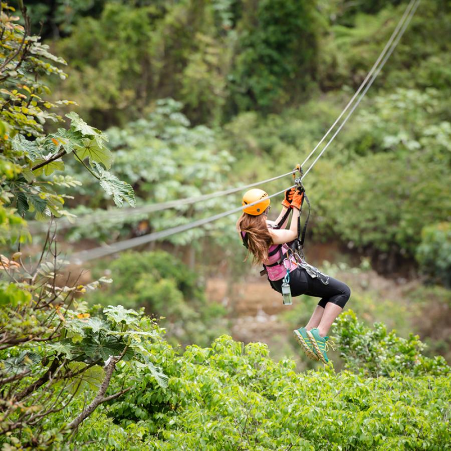 A woman ziplining over lush vegetation in Orocovis.