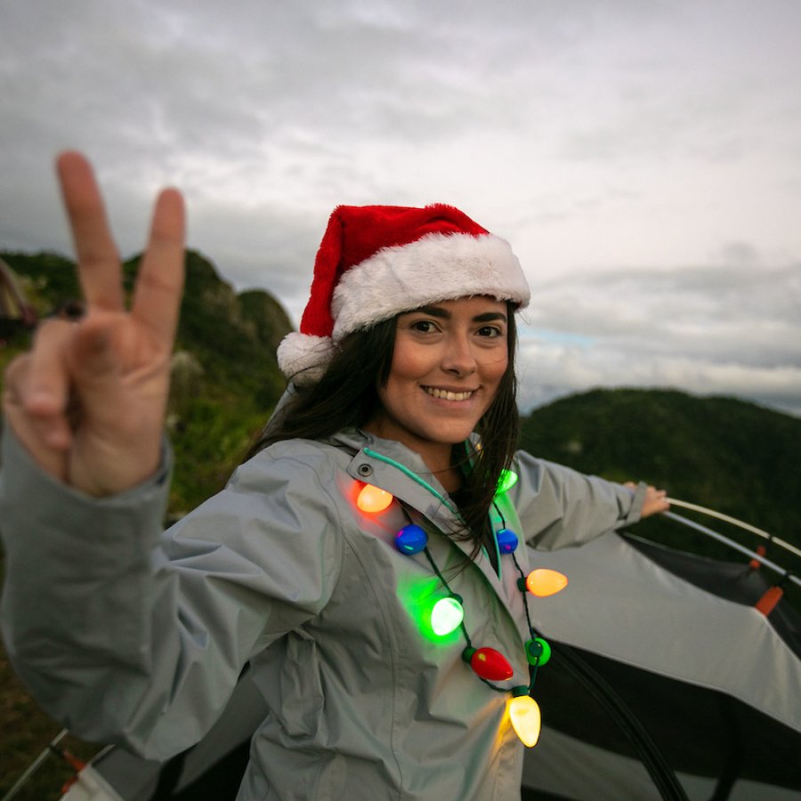 A woman wears a Santa Claus hat with a Christmas lights necklace 