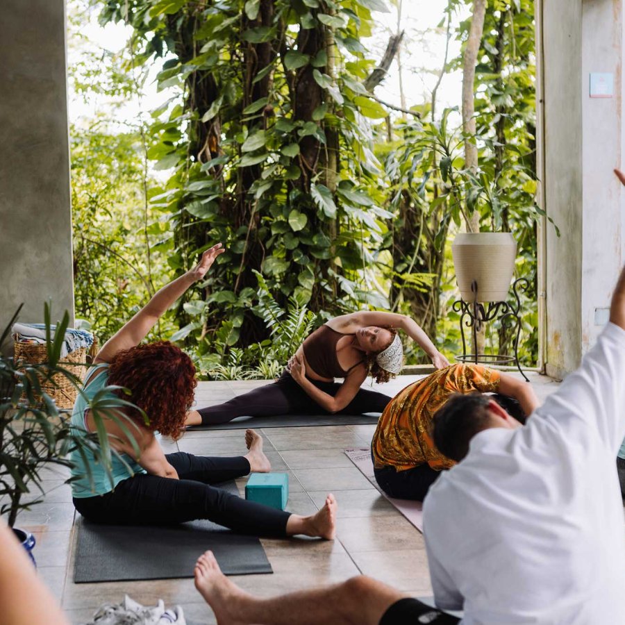 A group of people participate in a yoga class on a lush outdoor patio at Dos Aguas, a boutique hotel in Río Grande, Puerto Rico.