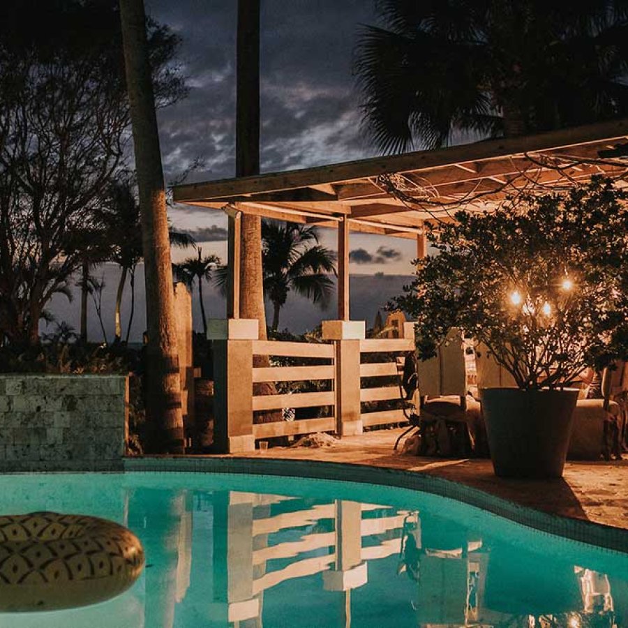 A patio overlooking a pool in a tropical setting is illuminated at night. Villa Montana Beach Resort, Aguadilla, Puerto Rico.