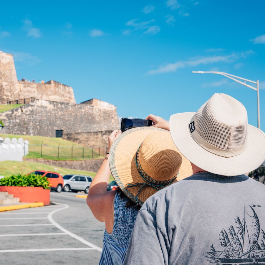 Una pareja, una mujer y un hombre, tomando fotos de monumentos históricos en el Viejo San Juan.