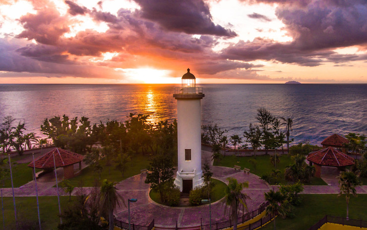 The sun sets behind a lighthouse in Rincón.