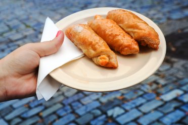 A woman's hand holding a plate with quesitos, traditional Puerto Rican pastries.