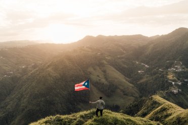 man in the mountains with Puerto Rico flag