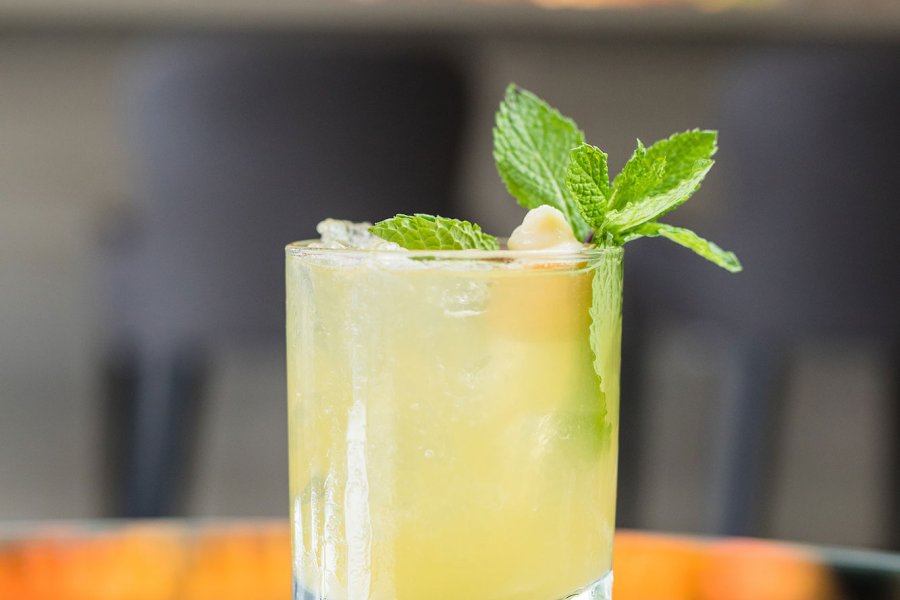 A lime-colored rum cocktail with a green garnish sits on a table.
