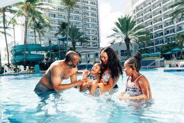 A family plays together in a pool.