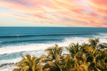 The sun setting, painting the sky a color of orange and pink, over the pristine waters of the beaches in Aguadilla, Puerto Rico.