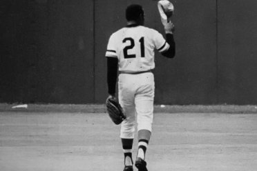 Roberto Clemente in the baseball field with a hat off.