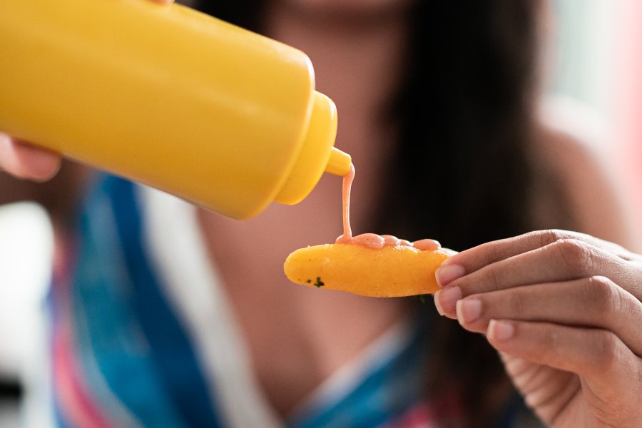 Woman pouring sauce on a sorullito.
