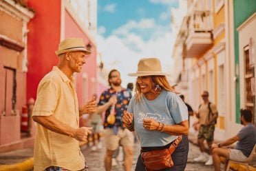 People smiling and dancing on a colorful street in Old San Juan.