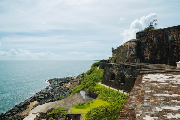 Historic stone walls of Castillo San Felipe del Morro overlooking the Atlantic Ocean in Old San Juan, Puerto Rico, with the Puerto Rican and U.S. flags flying above the fort.