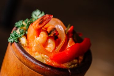 Puerto Rican seafood dish served in a traditional wooden pilón, featuring shrimp, peppers, and savory island-seasoned sauce.