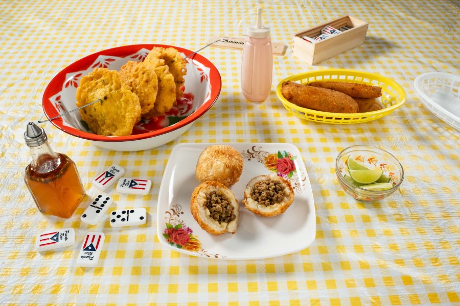 Three fried foods at the top of the table accompanied by some vinegar, mayo-ketchup, lime and dominos.