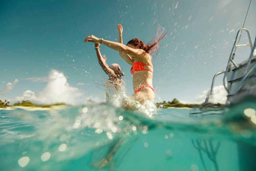 Two travelers leap from a boat into the crystal-clear waters of Icacos Island in Fajardo, Puerto Rico, splashing into the turquoise sea on a sunny day.