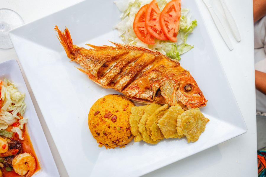 Whole fried snapper served with seasoned rice, tostones, lettuce, and tomato in Guayama, Puerto Rico.