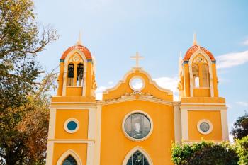 La iglesia de estilo misión española de color amarillo brillante con vista a la plaza del pueblo en Añasco