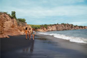 A group of women walk along Playa Negra black sand beach in Vieques, Puerto Rico