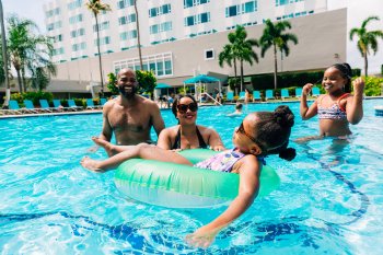 A family with two parents and two kids plays in a resort pool in Puerto Rico.