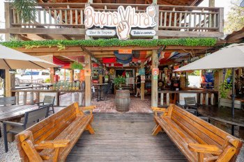 Exterior of a two-story beach bar and restaurant in Cabo Rojo, Puerto Rico, with two wooden benches sitting in the front.