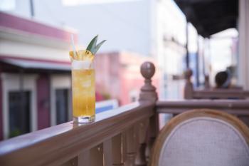 A craft cocktail sits on a balcony railing at The Mezzanine in Old San Juan.