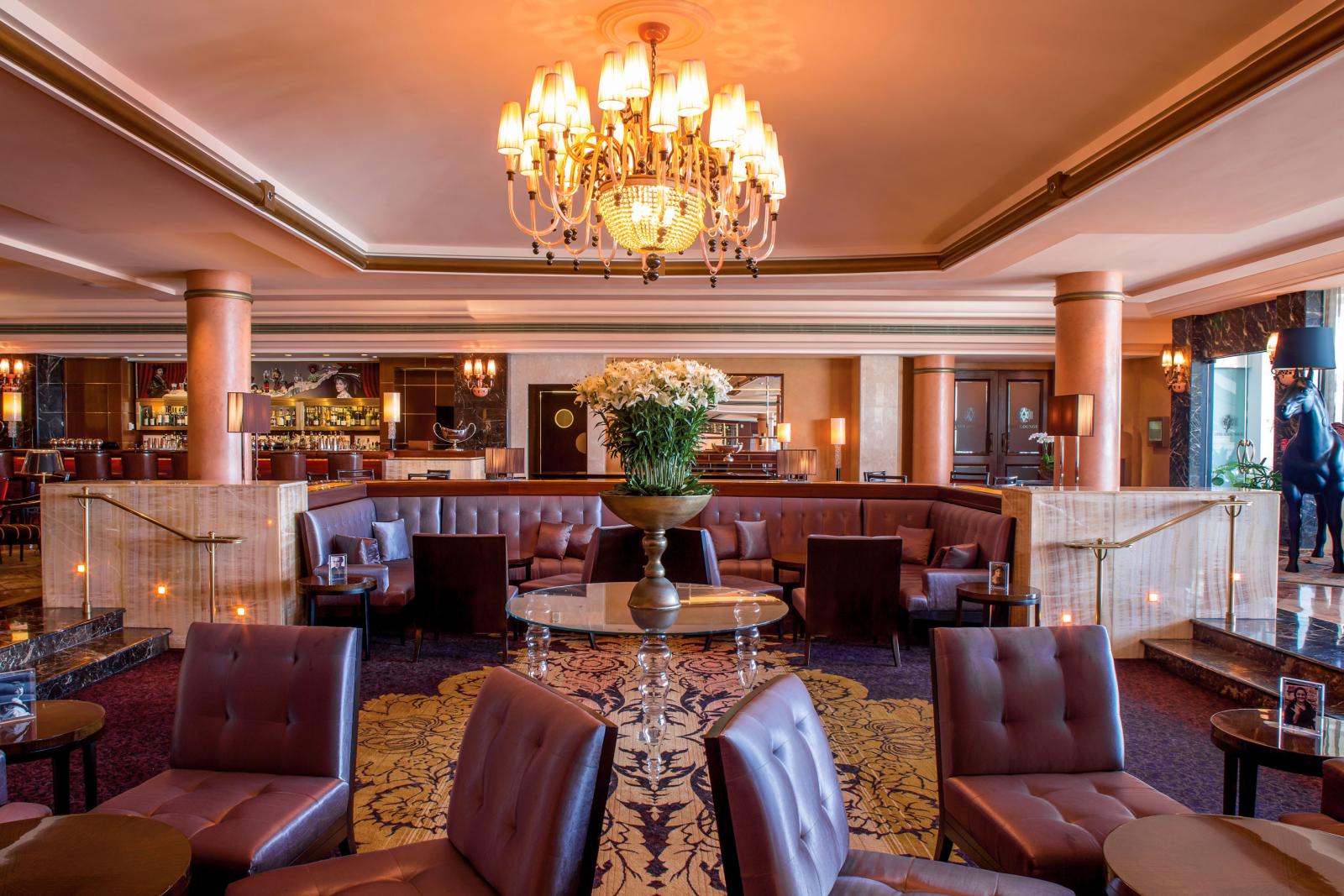 The elegant lounge at the Condado Vanderbilt hotel includes leather upholstery, marble columns and an ornate chandelier.