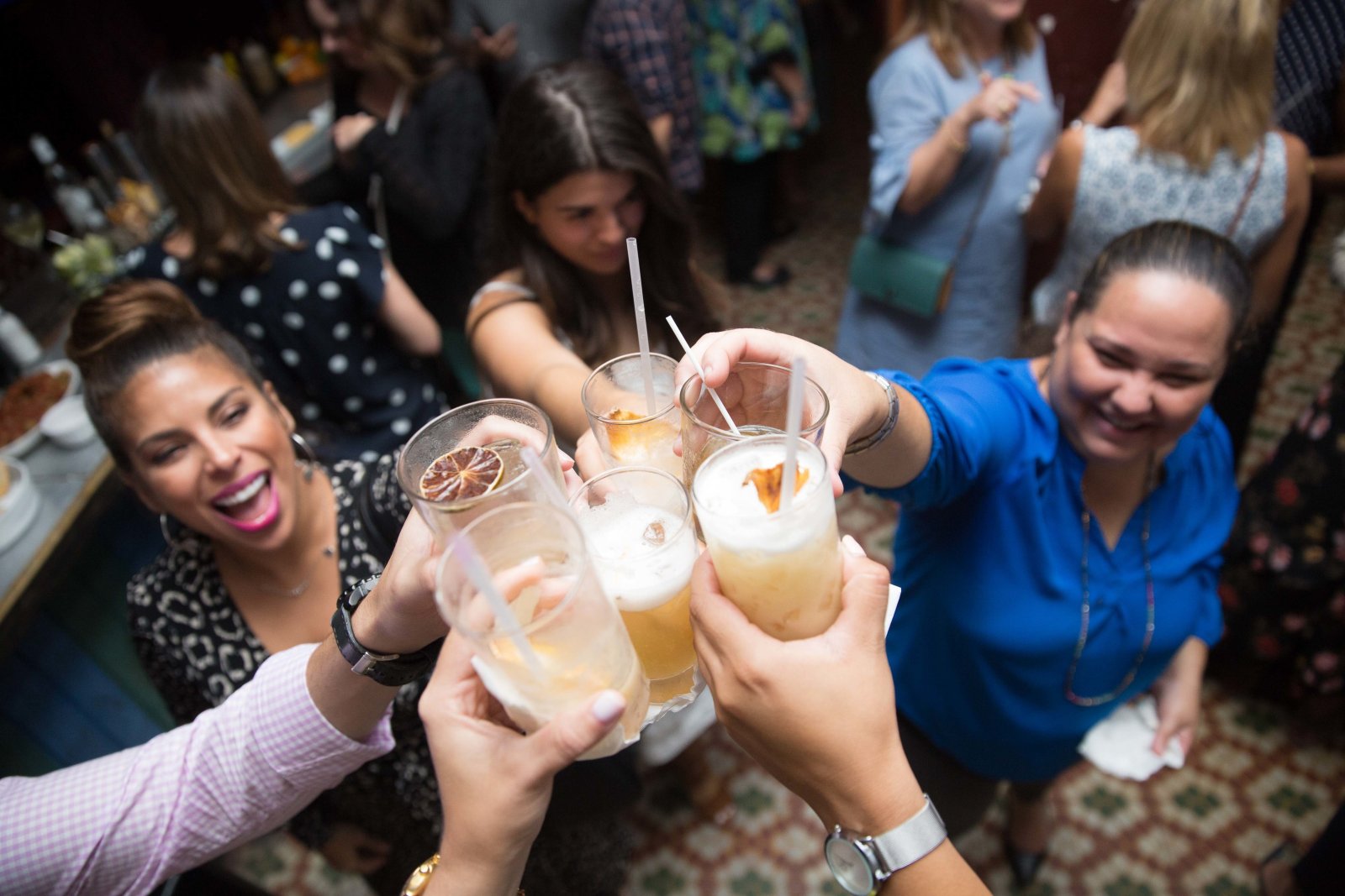 A group of friends toasts their drinks at a bar.