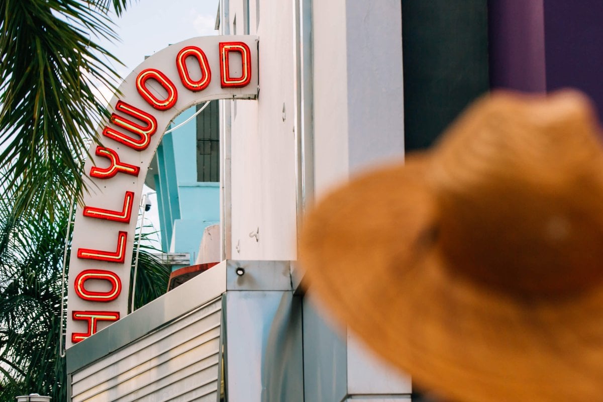 Woman in a hat standing outside the historic Hollywood Theater in Coamo.