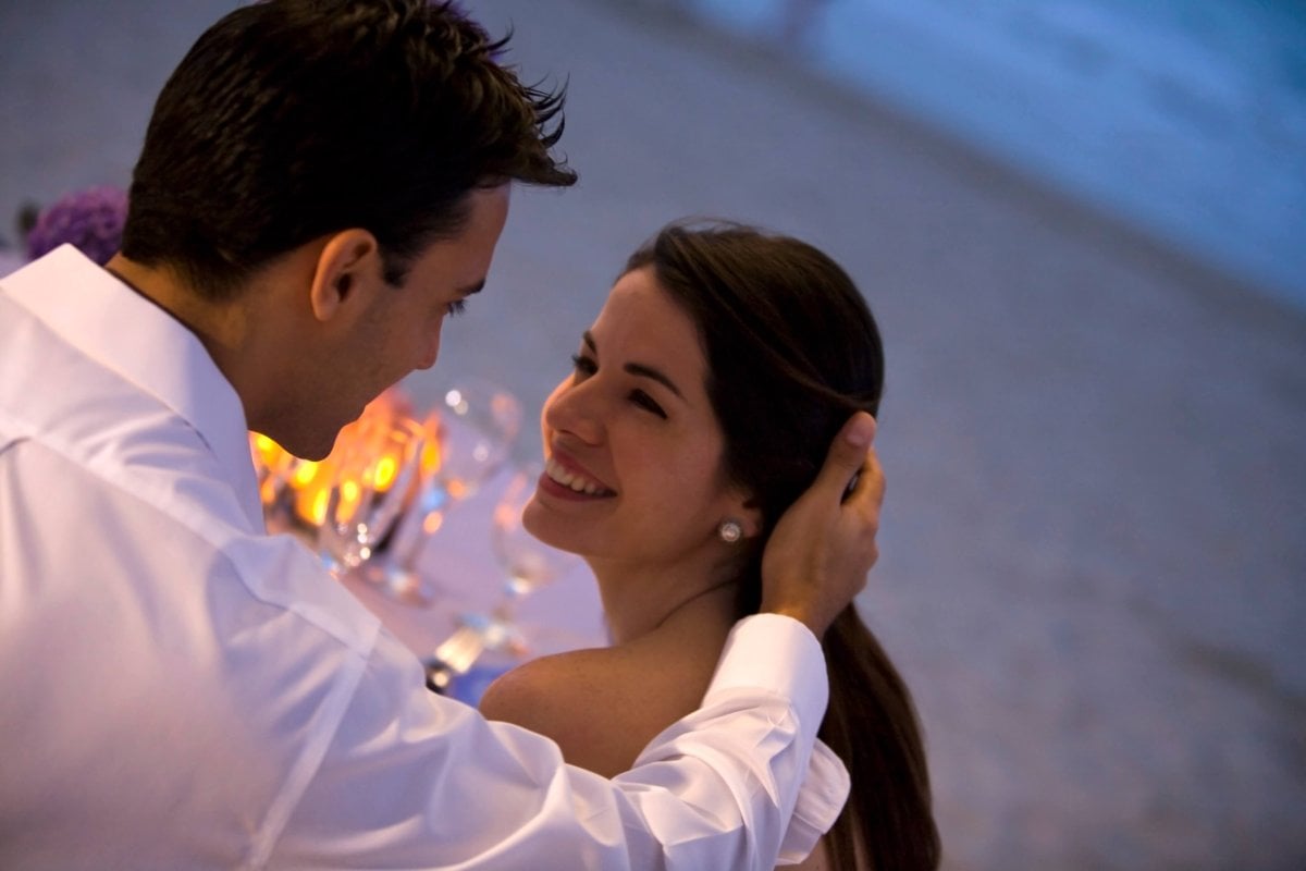 Wedding couple gazing lovingly at each other on the beach.
