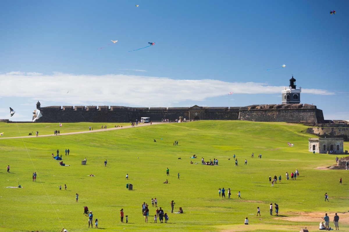 Multitudes disfrutando de un día soleado en un campo fuera del Castillo San Felipe del Morro en San Juan.