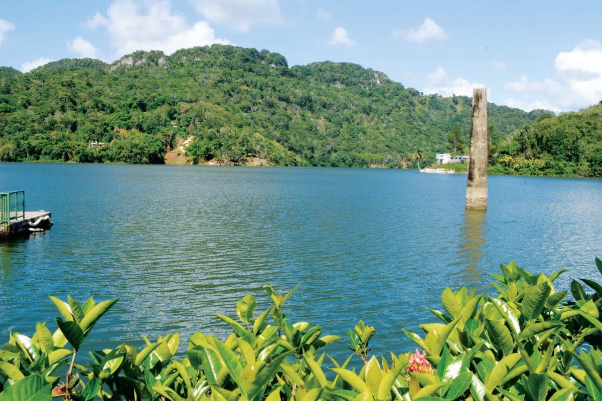 Sunny day at Lago Dos Bocas, surrounded by mountains and vegetation. 