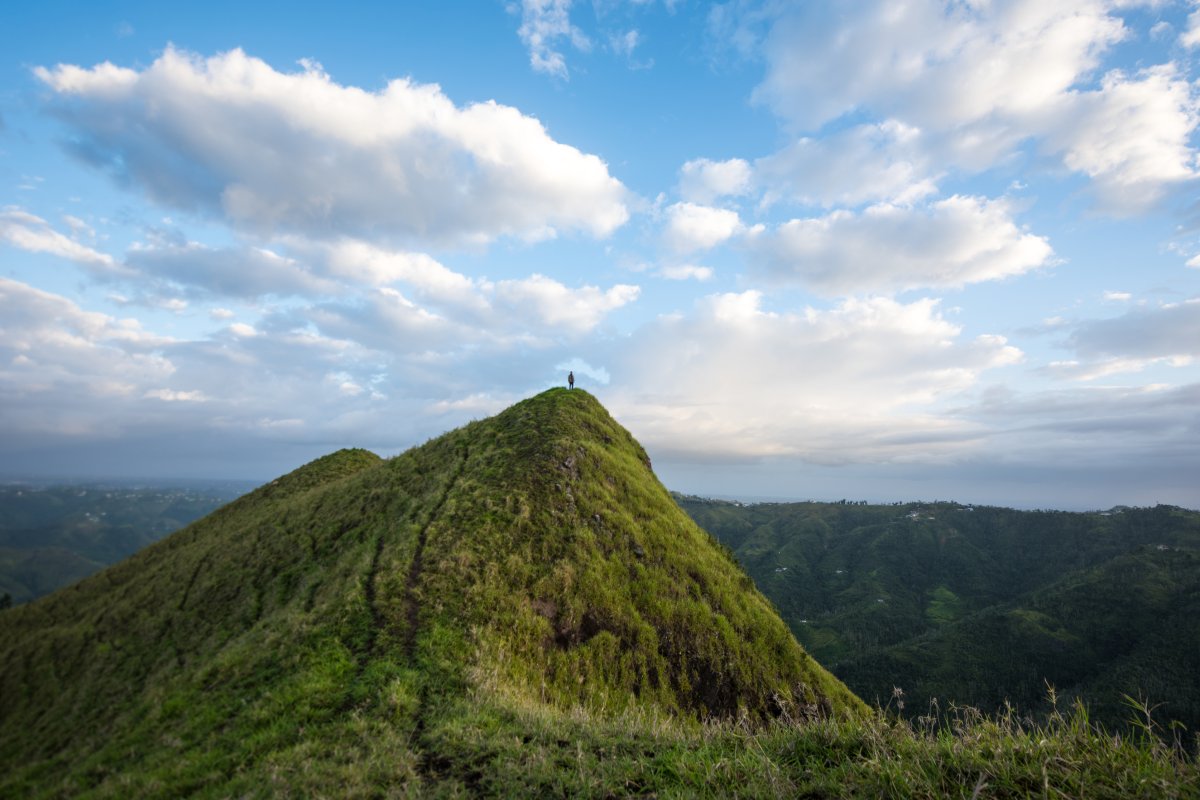 A person stands at the peak of mountain in the central region of puerto rico.