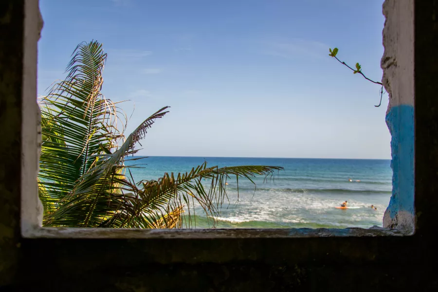 Poised and ready, a surfer scans the horizon at Surfer's Beach in Aguadilla, known for its consistent surfing in Puerto Rico.