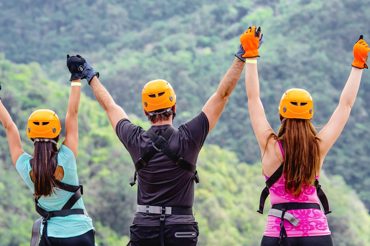 A group of people with arms raised celebrate at the top of Toro Verde Adventure Park.