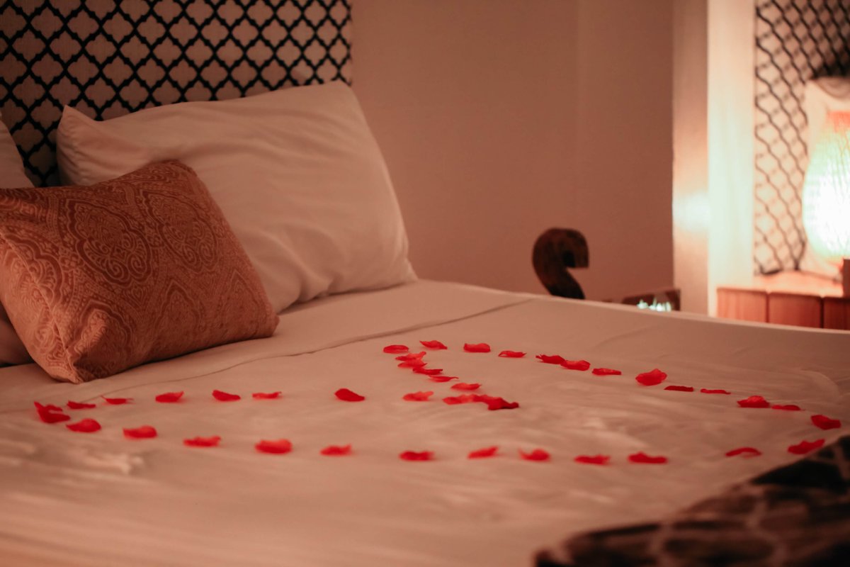 Rose petals form a heart on a bed at the Serenity Hotel.