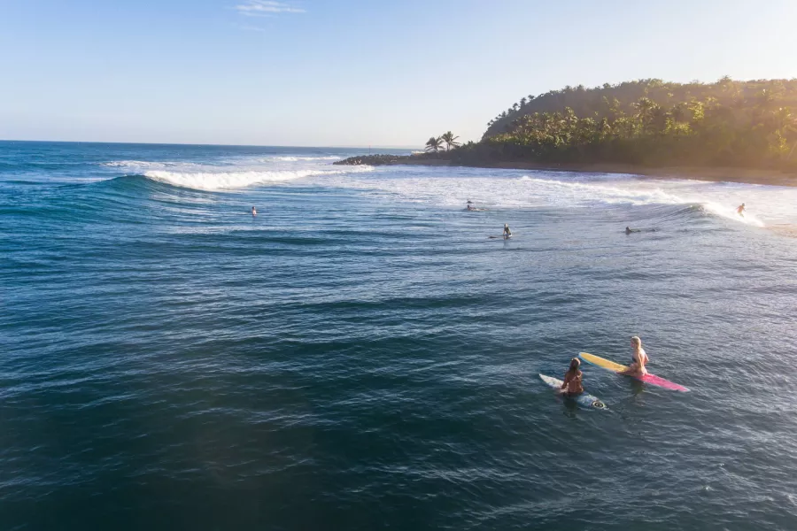 Anticipation builds as two surfers await the next set at Domes Beach in Rincón, a renowned Puerto Rican surf spot.