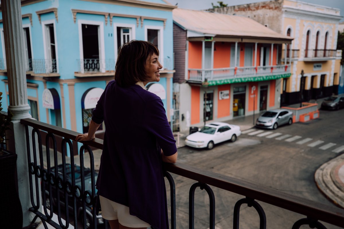 a woman stands on a balcony overlooking a street in ponce