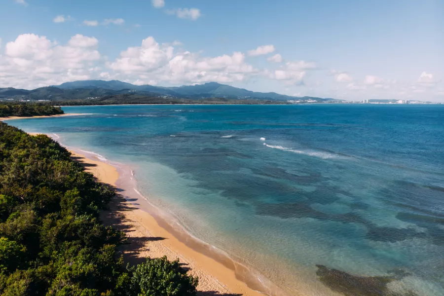an aerial view of the golden sand and bright blue water of escondida beach in fajardo