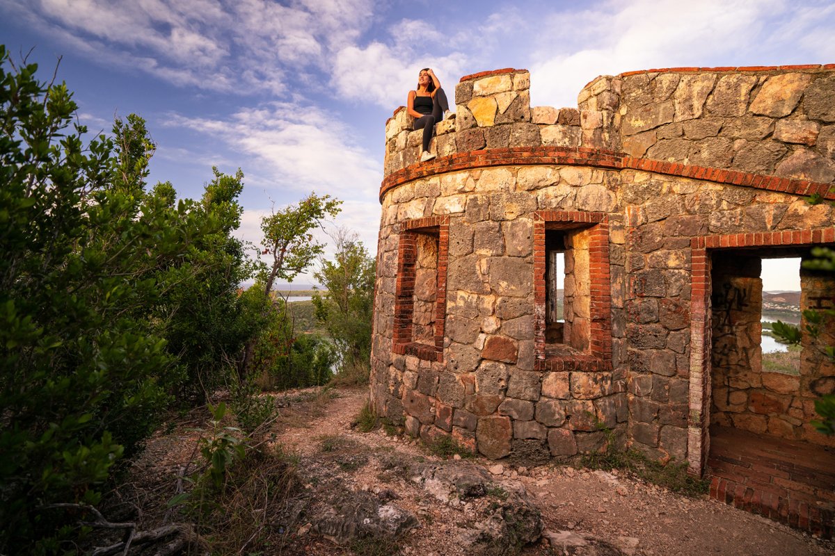 A woman sits on top of a historic fort in the Guánica Dry Forest.