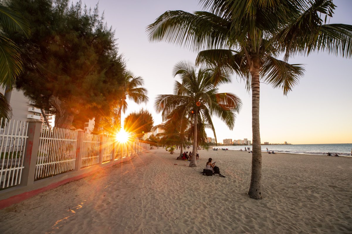 El sol se pone detrás de las palmeras en la playa de Isla Verde en Carolina, Puerto Rico.